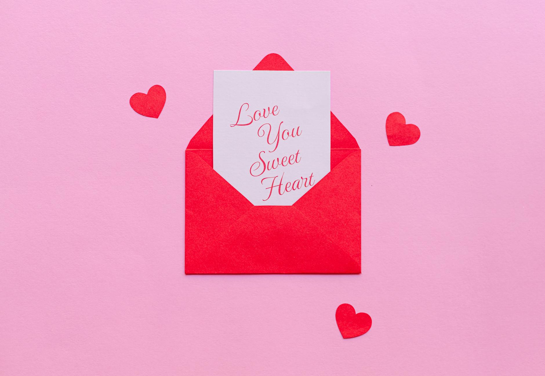 A red envelope with a love letter on pink background, ideal for Valentine's.