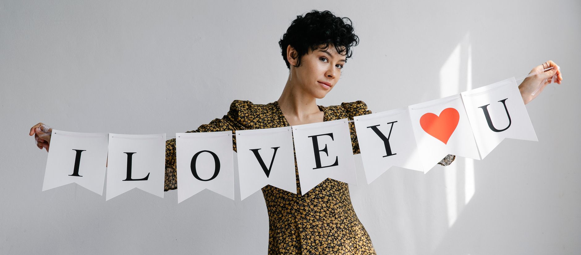 Charming female demonstrating flag garland with i love you phrase for Valentine Day and looking at camera