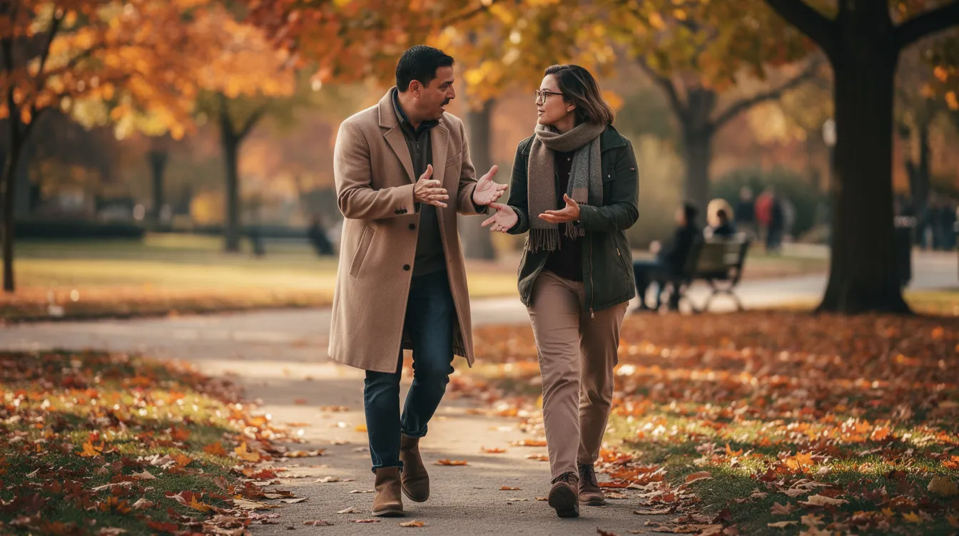 Zwei Personen gehen nebeneinander in einem herbstlichen Park, umgeben von buntem Laub, und führen ein lebhaftes Gespräch, während sie gestikulieren. Die Atmosphäre ist entspannt und fröhlich, ideal für ein erstes Date mit vielen interessanten Gesprächsthemen.
