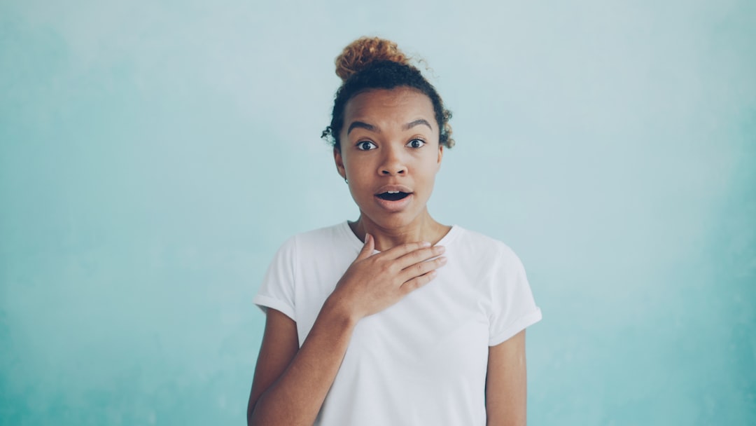 Young woman with hand on chest, surprised expression.